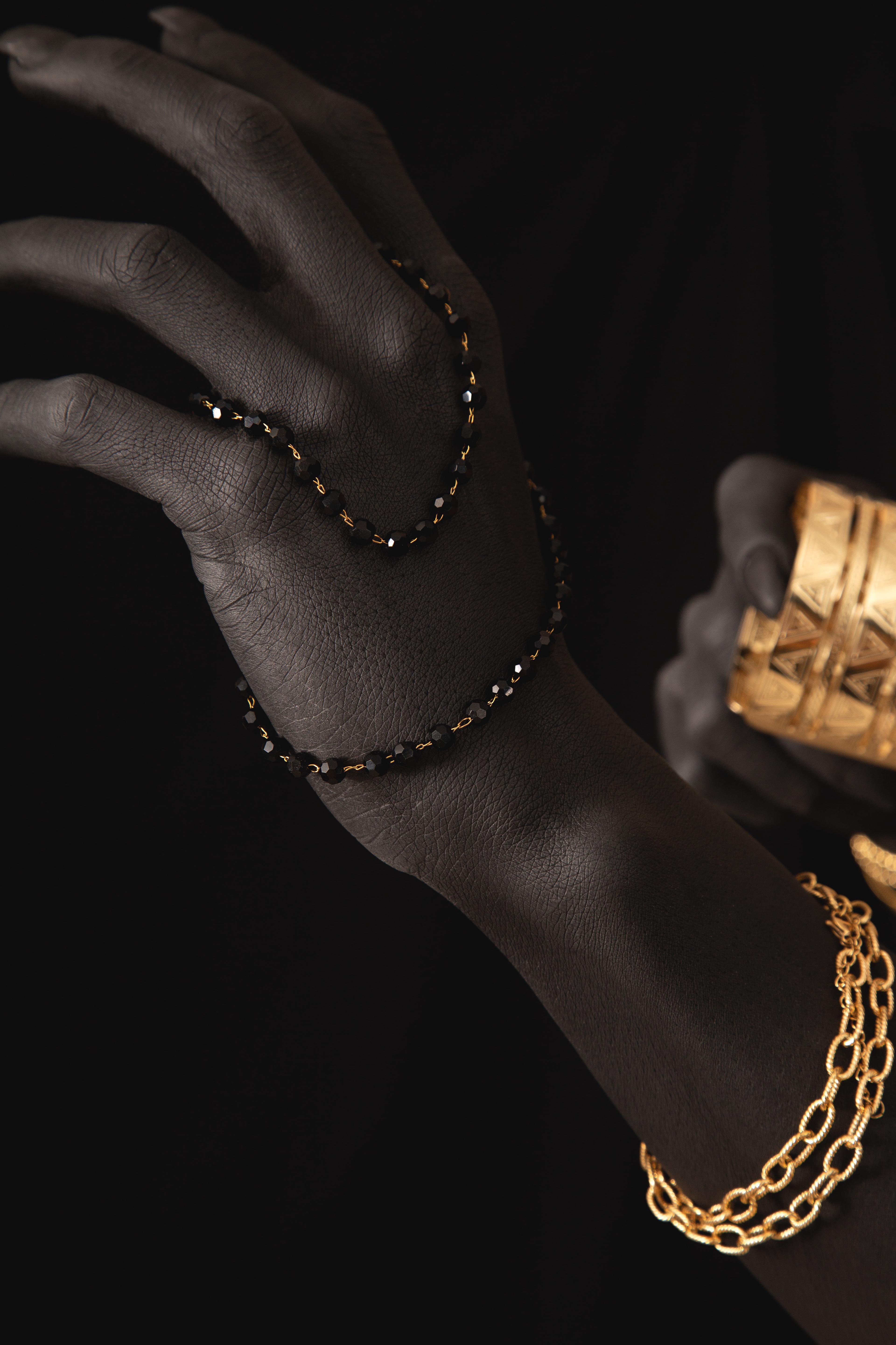 Bracelets en or et perles noires sur main noire