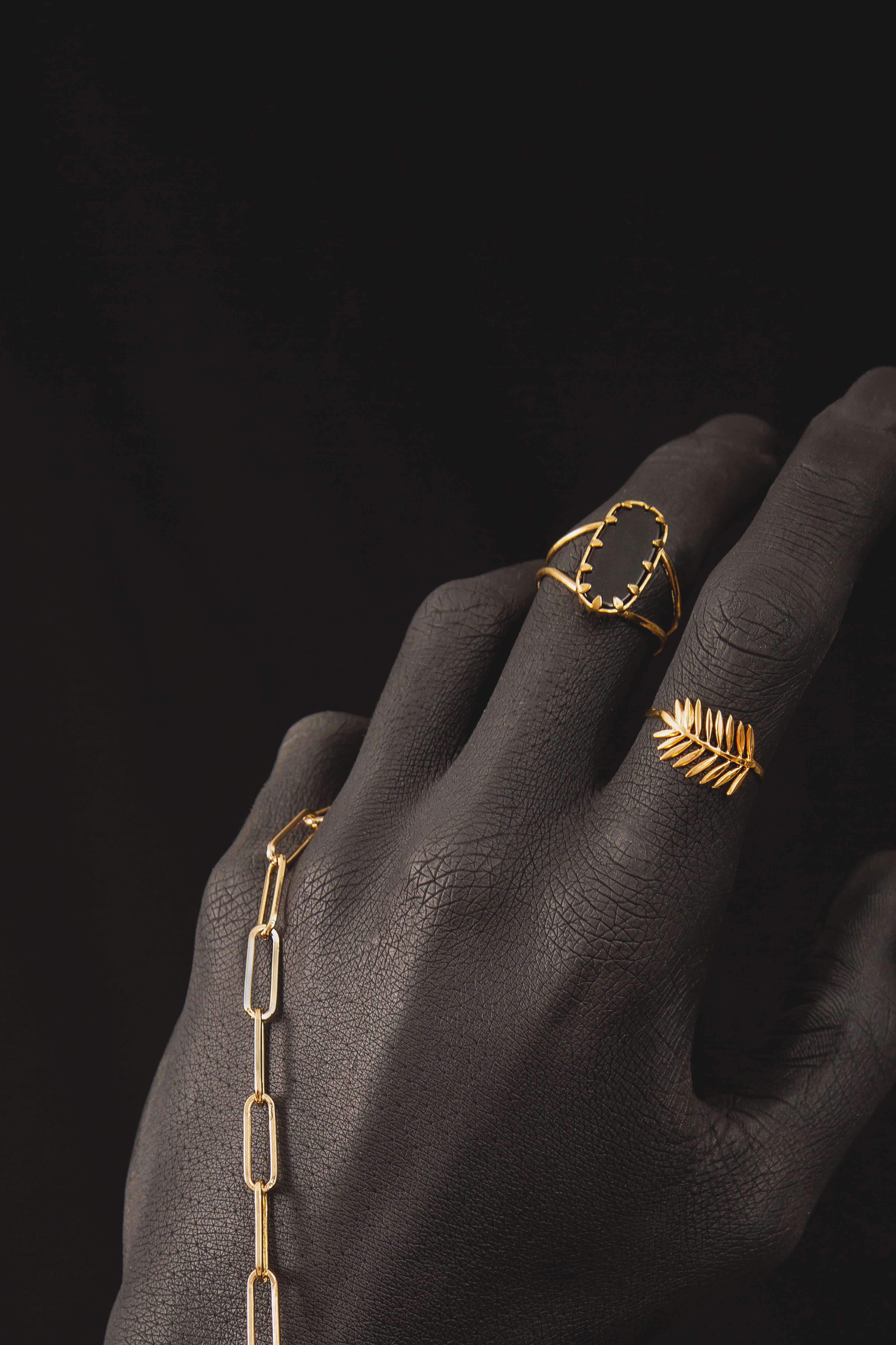 Bague dorée sur main noire avec pierre noire taillée