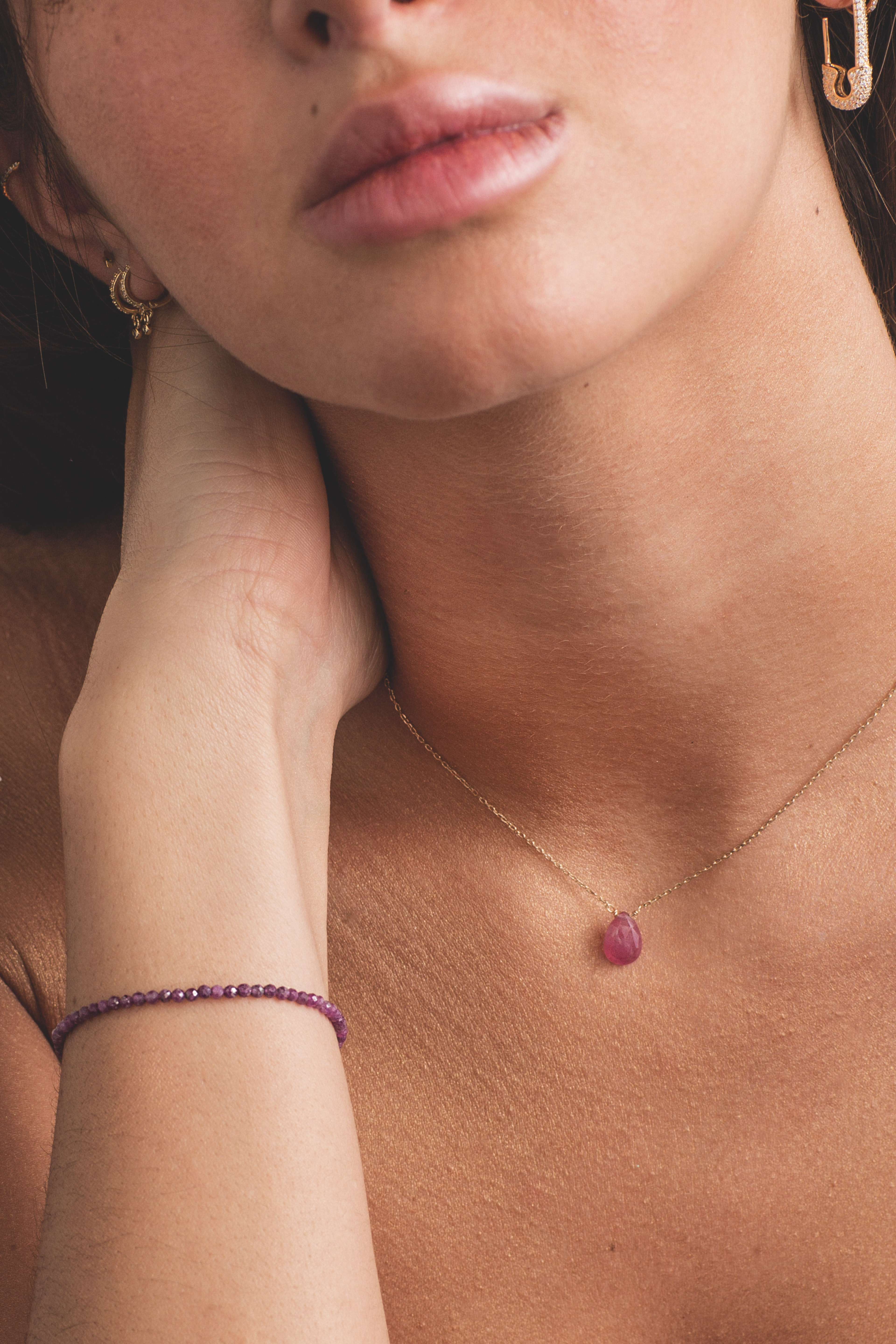 Portrait d’une femme portant un collier avec pendentif rose et boucle d’oreille dorée