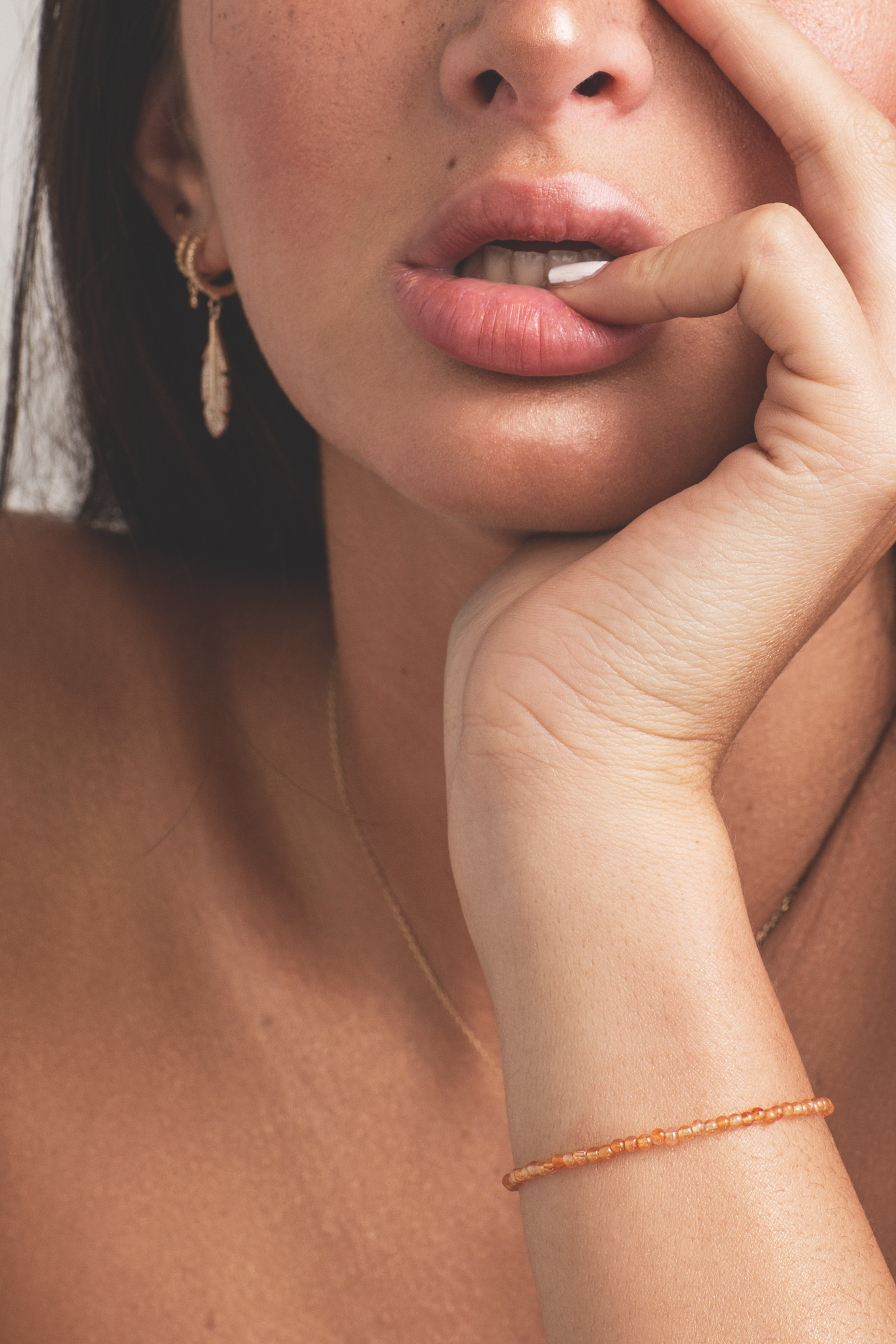 Gros plan sur femme portant un bracelet fin orange et boucles d'oreilles
