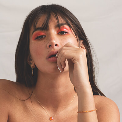 Femme portant un collier fin et des boucles d’oreilles en or