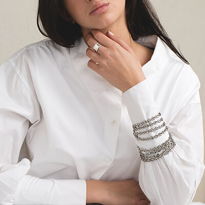 Femme en chemise blanche portant une bague et des bracelets argentés