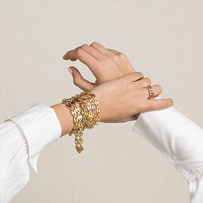 Poignets croisés ornés de bracelets dorés empilés