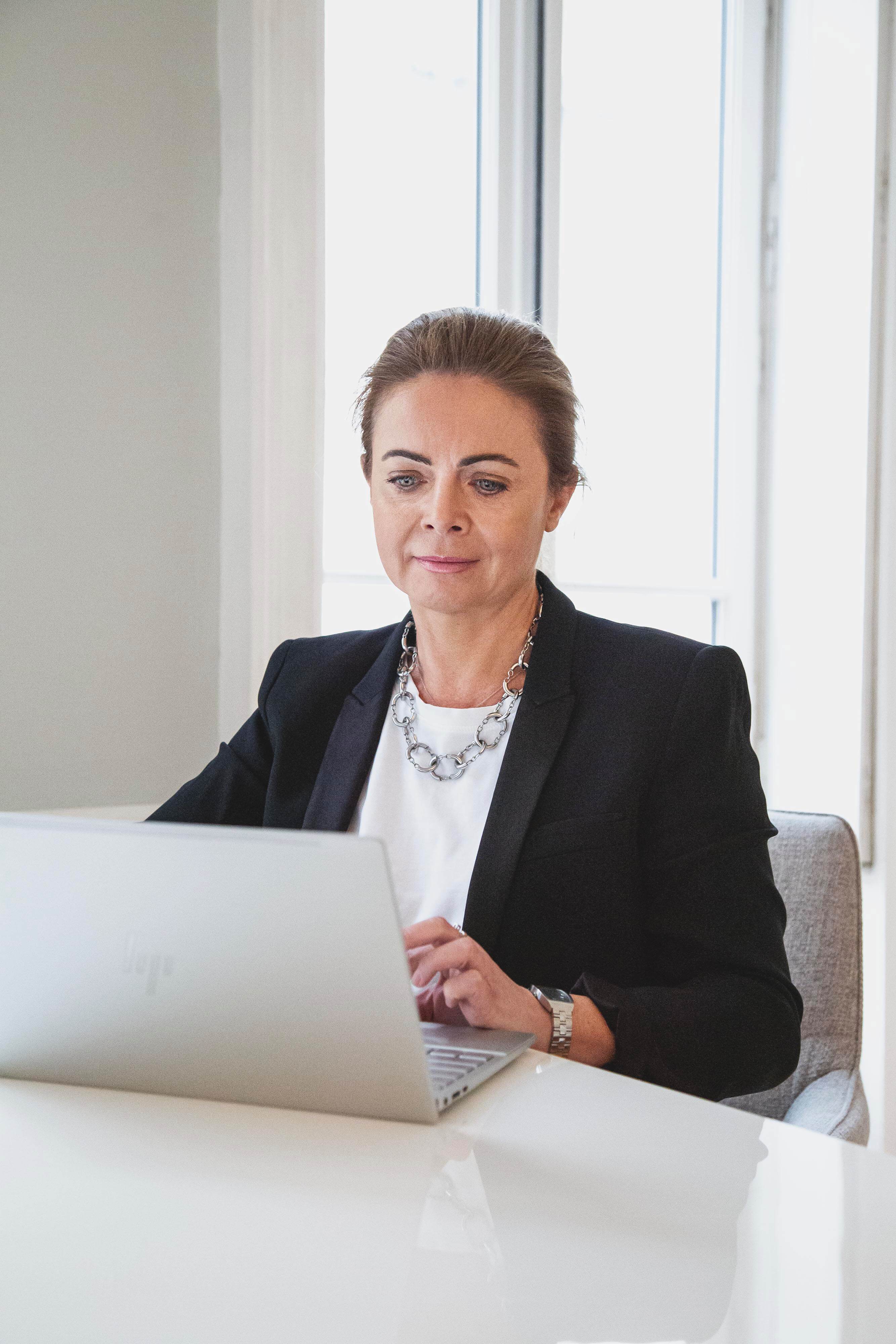 Femme en blazer noir travaillant sur un ordinateur