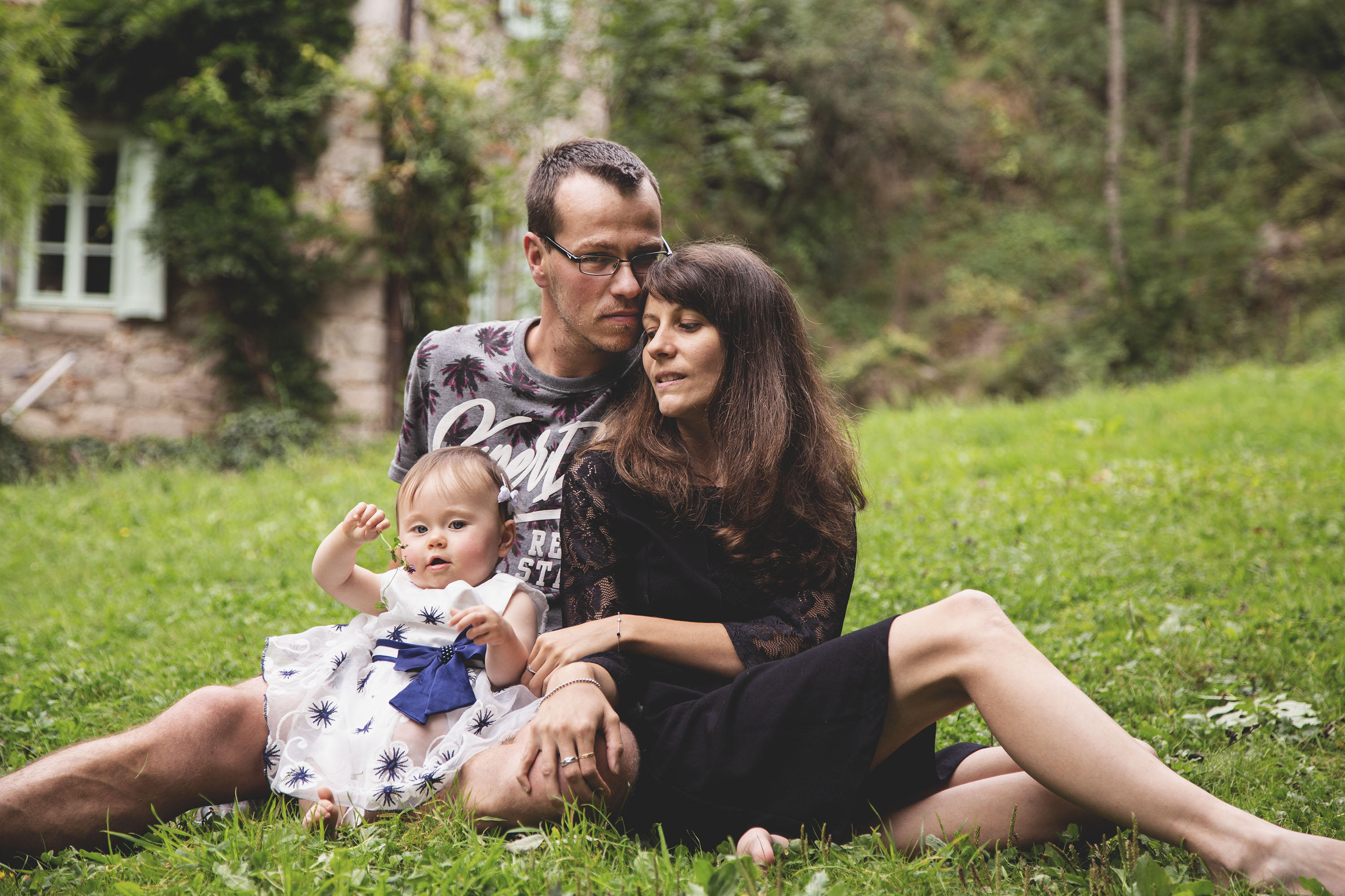 Famille assise sur l’herbe avec leur petite fille